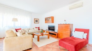 A living room with a sofa, armchair, TV, and a cabinet. - Apartment Praia Dona Ana (Lagos)