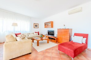A living room with a sofa, armchair, TV, and a cabinet. - Apartment Praia Dona Ana (Lagos)