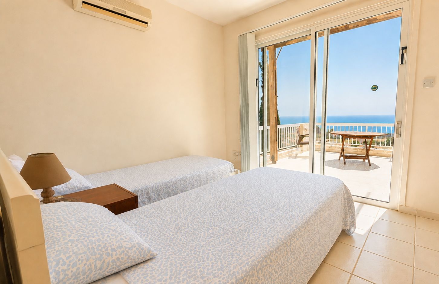 Une chambre d’hôtel avec deux lits, une table et vue sur la mer.