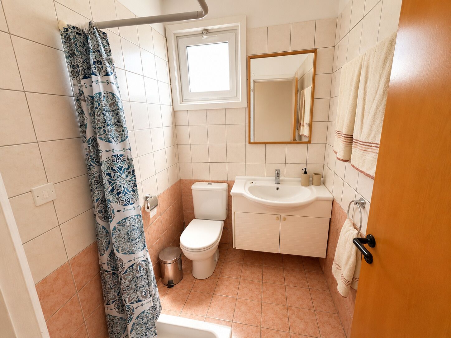 Et badeværelse med toilet, håndvask og bruseforhæng.
