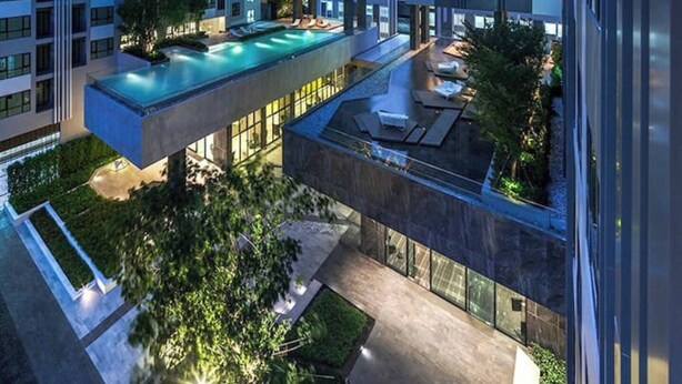 Un edificio de gran altura con varios balcones y una piscina en la azotea.