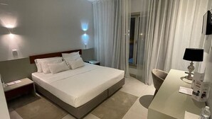 A hotel room with a bed, bedside tables, a desk, and a chair.