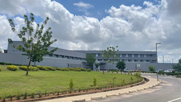 A modern building with a curved facade, a well-maintained lawn, and a clear sky.