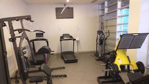 A gym with various exercise equipment including treadmills, a weight bench, and a squat rack.