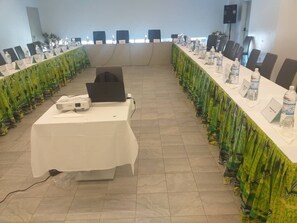 A conference room with a long table, chairs, a projector, and water bottles.