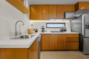 Eine moderne Küche mit Holzschränken, Edelstahlgeräten und einem Fenster über der Spüle.