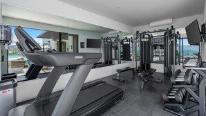 Ett modernt gym med löpband, styrketräningsmaskiner och en träningsbänk.