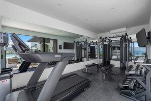Ein modernes Fitnessstudio mit Laufband, Kraftgeräten und einer Gewichtbank.