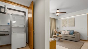 Ett kompakt bostadsutrymme med ett litet kök, en soffa, ett soffbord och en takfläkt.