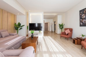 A modern living room with a sofa, armchair, coffee table, and a flat-screen TV. - Premium 3BR Residence in Sodic Eastown, New Cairo /Sleeps 8 (Cairo Governorate)