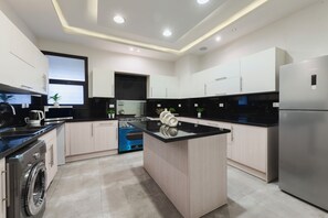 A modern kitchen with a central island, built-in appliances, and a view to the dining area. - Premium 3BR Residence in Sodic Eastown, New Cairo /Sleeps 8 (Cairo Governorate)
