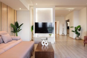 A modern living room with a flat-screen TV mounted on a white console, a beige sofa, and a wooden coffee table. - Premium 3BR Residence in Sodic Eastown, New Cairo /Sleeps 8 (Cairo Governorate)