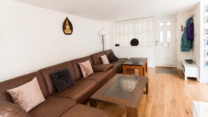 Ein modernes Wohnzimmer mit einem braunen Ledersofa, einem Couchtisch mit Glasplatte und einer weißen Tür mit Fenster.