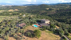 Una extensa propiedad con varias construcciones, una piscina y vastos olivares.