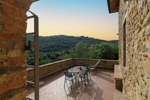 A patio with a table and chairs, overlooking a hilly landscape. - Authentic Umbrian Escape with Pool & Olive Grove (Umbria)