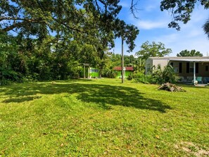 A grassy outdoor area with a building and a structure with a red roof. - Perdido Hideaway in Pensacola (Pensacola)