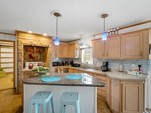 A modern kitchen with granite countertops, wooden cabinets, and a central island with stools. - Perdido Hideaway in Pensacola (Pensacola)