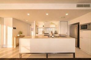 A modern kitchen with a central island, built-in appliances, and a clean, minimalist design. - Luxury Suite| Surfers Paradise|Ocean Views (Surfers Paradise)