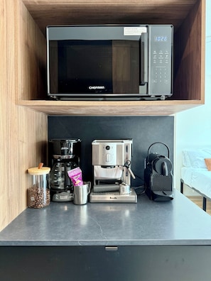 Una kitchenette equipada con microondas, cafetera y máquina de espresso.