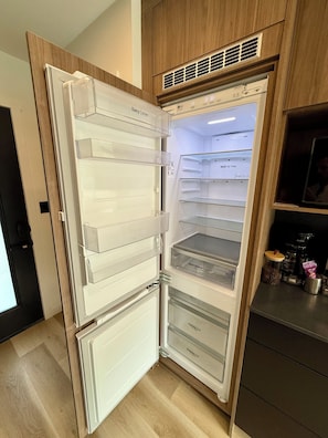 Una cocina moderna con refrigerador empotrado, armarios de madera y cafetera sobre la encimera.