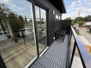 Un balcón moderno con puerta de cristal y barandilla de metal.