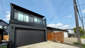 Une maison moderne à deux  étages, dotée d’un grand garage, d’une cour arrière clôturée et d’un poteau électrique bien visible.
