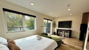 Une chambre d’hôtel moderne dotée d’un grand lit, d’un coin salon, d’une télévision et offrant une vue sur l’extérieur.