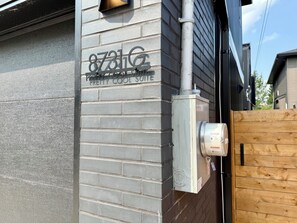 A building with a grey brick exterior and a sign that reads '8731G Pretty Cool Suite.'