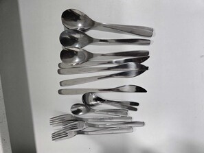 Une collection de couverts disposée verticalement sur une surface blanche.