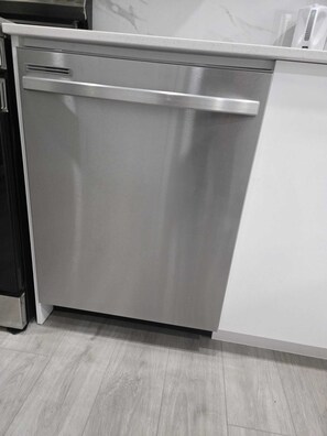 Eine spülmaschinenfeste Geschirrspülmaschine in einer Küche mit weißer Arbeitsplatte und hellem Holzboden.