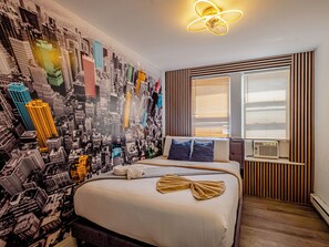 Habitación de hotel con cama, un mural de paisaje urbano, una ventana con persianas y una lámpara moderna.