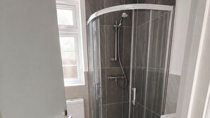 A modern bathroom with a glass shower enclosure, a toilet, and a sink. - Serviced Townhome: 4 bedroom, 3 bathroom+ garden (London)