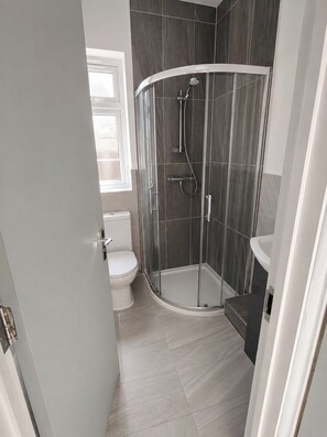 A modern bathroom with a glass shower enclosure, a toilet, and a sink. - Serviced Townhome: 4 bedroom, 3 bathroom+ garden (London)