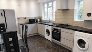 A modern kitchen with a dishwasher, oven, and a built-in washing machine. - Serviced Townhome: 4 bedroom, 3 bathroom+ garden (London)