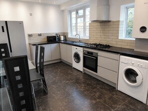 A modern kitchen with a dishwasher, oven, and a built-in washing machine. - Serviced Townhome: 4 bedroom, 3 bathroom+ garden (London)