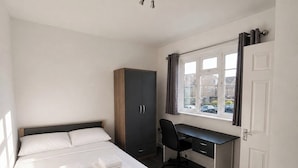 A bedroom with a bed, a desk, and a wardrobe. - Serviced Townhome: 4 bedroom, 3 bathroom+ garden (London)
