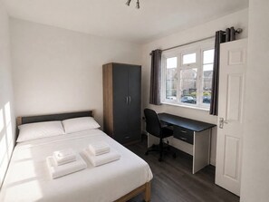 A bedroom with a bed, a desk, and a wardrobe. - Serviced Townhome: 4 bedroom, 3 bathroom+ garden (London)