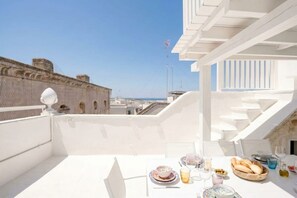 A rooftop terrace with a table set for dining, overlooking a cityscape. - Luxury 4BR Palazzo with Rooftop Terrace in Monopoli (Monopoli)