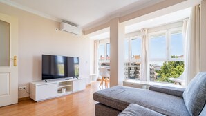 A modern living room with a flat-screen TV, a sofa, and a dining area with a view of the city. - Cubo's Central Bright Marbella Apartment / urban / free wifi (Marbella)