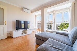 A modern living room with a flat-screen TV, a sofa, and a dining area with a view of the city. - Cubo's Central Bright Marbella Apartment / urban / free wifi (Marbella)