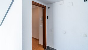 A hallway with a wooden door, a light switch, and a thermostat on the wall. - Cubo's Central Bright Marbella Apartment / urban / free wifi (Marbella)