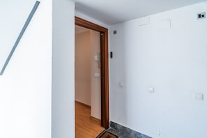 A hallway with a wooden door, a light switch, and a thermostat on the wall. - Cubo's Central Bright Marbella Apartment / urban / free wifi (Marbella)