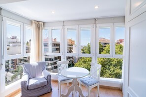A spacious balcony with a white chair, a round glass table, and a view of the cityscape. - Cubo's Central Bright Marbella Apartment / urban / free wifi (Marbella)