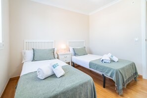Ett hotellrum med två separata sängar, ett nattduksbord med en lampa och en dörr.