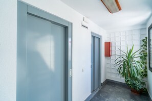 A hallway with two doors, a sign above the right door, a red cabinet, and a potted plant. - Cubo's Central Bright Marbella Apartment / urban / free wifi (Marbella)
