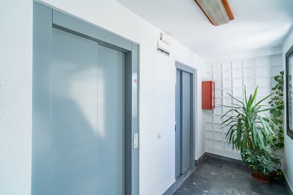 Ein Flur mit zwei Türen, ein Schild über der rechten Tür, einem roten Schrank und einem Blumentopf.