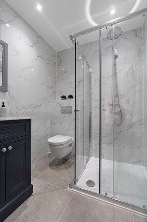 A modern bathroom with a glass-enclosed shower, a toilet, and a vanity with a mirror. - Modern Apartment in City Centre (Edinburgh)