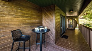 A wooden corridor with a table and chairs, a bench, and a view of a garden. - NEW Couples! VIEW, Barrel Sauna, Hot Tub, Fire Pit (Sevierville)