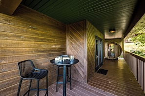 A wooden corridor with a table and chairs, a bench, and a view of a garden. - NEW Couples! VIEW, Barrel Sauna, Hot Tub, Fire Pit (Sevierville)