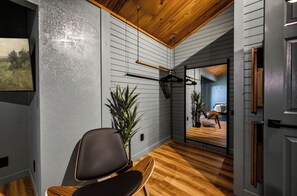 A room with a wooden ceiling, a wall-mounted rack, a chair, and a potted plant. - Couples Winter Haven | VIEW, Barrel Sauna, Hot Tub (Sevierville)